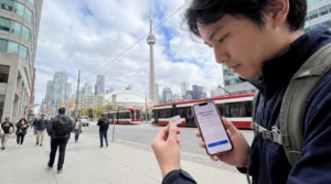 Tourist comparing local SIM card and eSIM on smartphone in Toronto Canada with CN Tower skyline