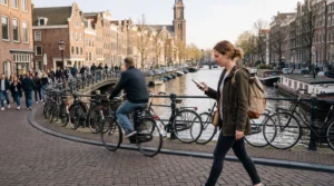 Tourist using mobile internet on smartphone while walking along Amsterdam canals in the Netherlands.