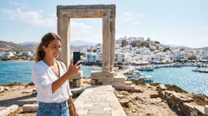 Tourist using an eSIM in Naxos near the Portara and Aegean Sea
