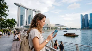 Tourist using mobile internet in Marina Bay Singapore with eSIM for maps, Grab and travel apps