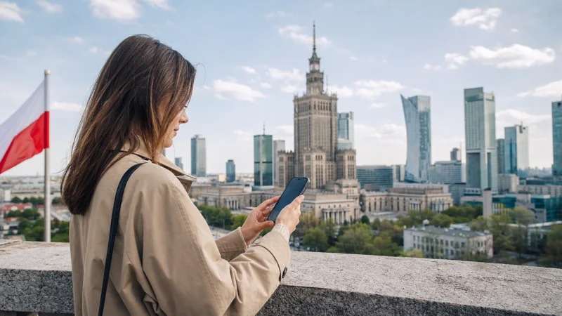 Traveller checking mobile service beside the Warsaw skyline in Poland.