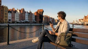Traveller using a smartphone beside the Motława waterfront in Gdańsk Poland.