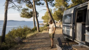 Campervan traveller using a phone at a Croatian coastal campsite.
