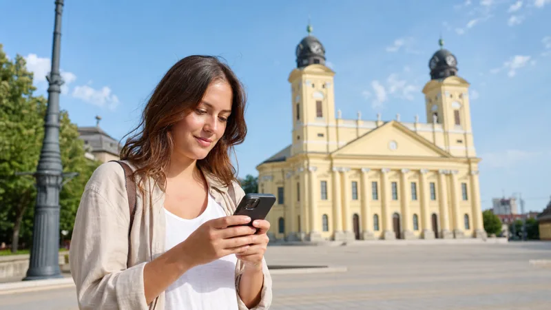 Tourist using mobile internet near the Great Reformed Church in Debrecen