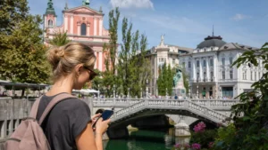 Tourist using a smartphone beside the Triple Bridge in Ljubljana.