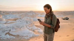 Tourist using mobile internet while visiting the White Desert in Egypt