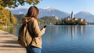 Traveller using a smartphone on a path beside Lake Bled.