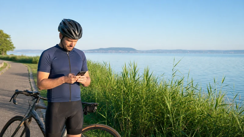 Traveller checking mobile data coverage on a smartphone beside Lake Balaton, Hungary