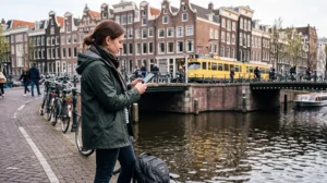 Traveler using mobile data in the Netherlands near an Amsterdam canal