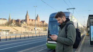 Traveller checking mobile data near a Szczecin tram.