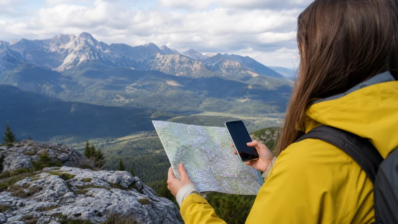 Tourist comparing an offline map and smartphone navigation at a Slovak scenic viewpoint.