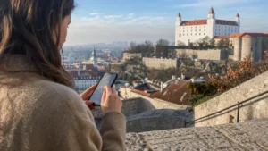 Traveller configuring an iPhone near Bratislava Castle before a day of sightseeing.