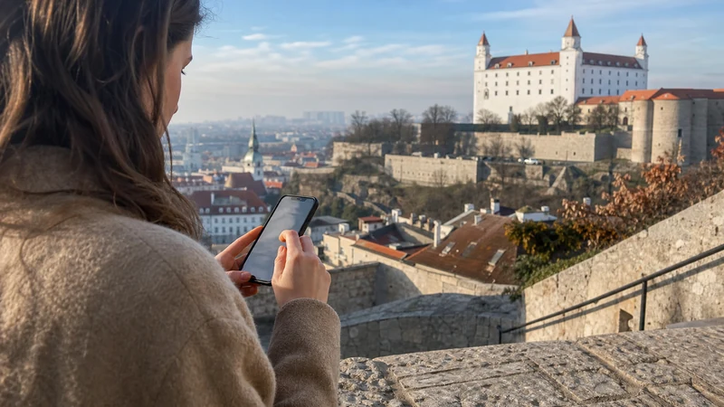 Traveller configuring an iPhone near Bratislava Castle before a day of sightseeing.