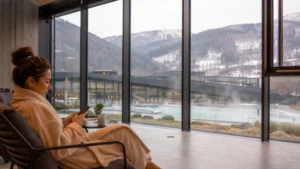Spa visitor checking a smartphone in a dry lounge overlooking a Slovak thermal resort.