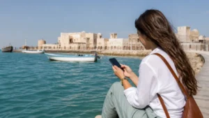 Traveller using a smartphone in visitor on Al Wakrah's traditional seafront