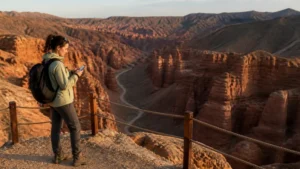 Hiker using a smartphone at a safe Charyn Canyon viewpoint.