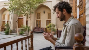 Traveller checking smartphone settings in a Bukhara courtyard.