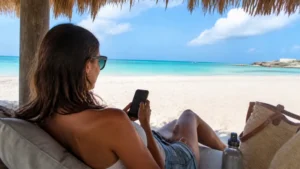 Traveller using a smartphone beside turquoise water in Aruba