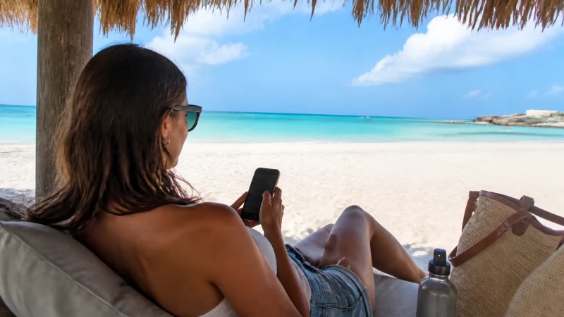 Traveller using a smartphone beside turquoise water in Aruba