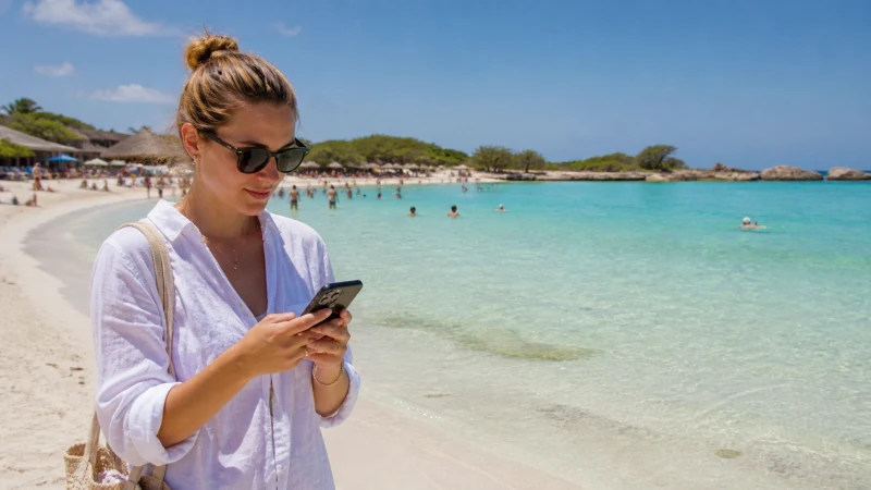 Traveller using mobile internet beside Baby Beach Aruba