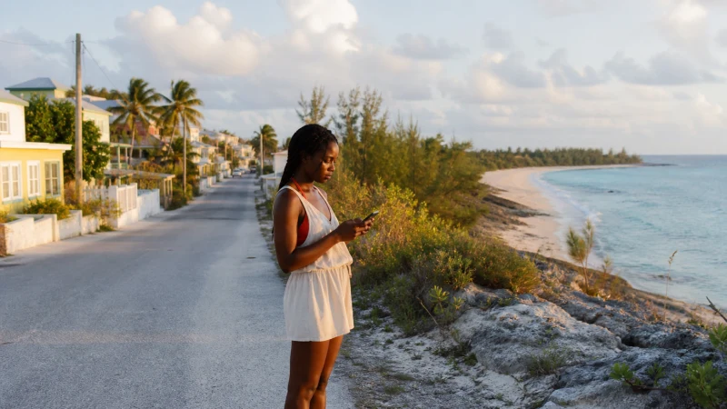 Traveller checking eSIM coverage beside a coastal road in The Bahamas