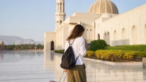 Traveller using a smartphone during solo Oman traveller with suitcase