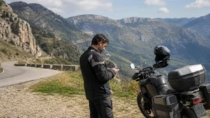 Motorcyclist checking a smartphone beside a parked motorcycle in Bulgaria
