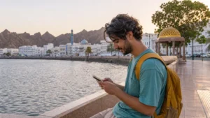 Traveller using a phone on muscat's muttrah corniche