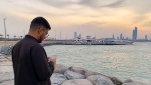 Traveller using a smartphone in a Kuwait setting related to how to stay online in fahaheel