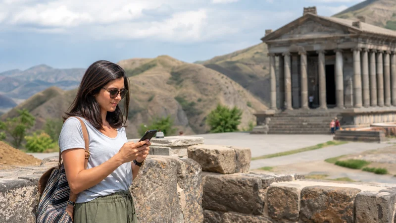Traveller using a smartphone while using mobile internet on a Garni and Geghard day trip