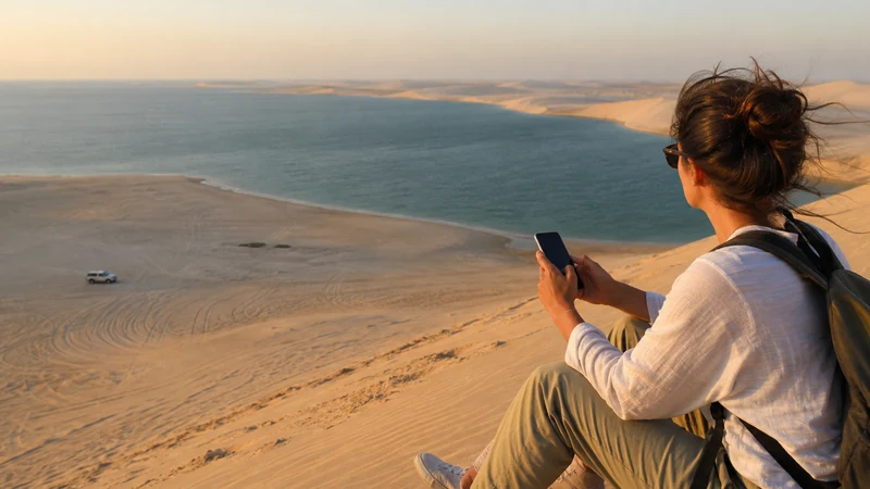 Traveller using a smartphone in guided traveller using a phone beside dunes overlooking the Inland Sea