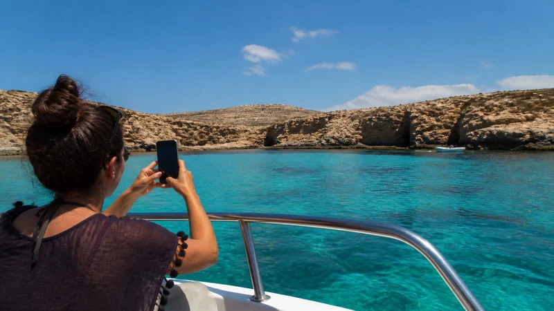 Traveller using a smartphone during a boat trip to Comino