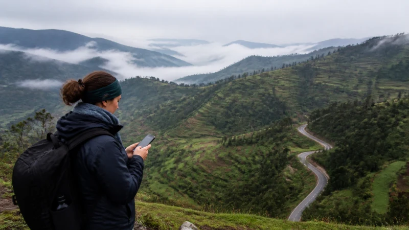 Traveller checking a smartphone above the misty hills near Gicumbi