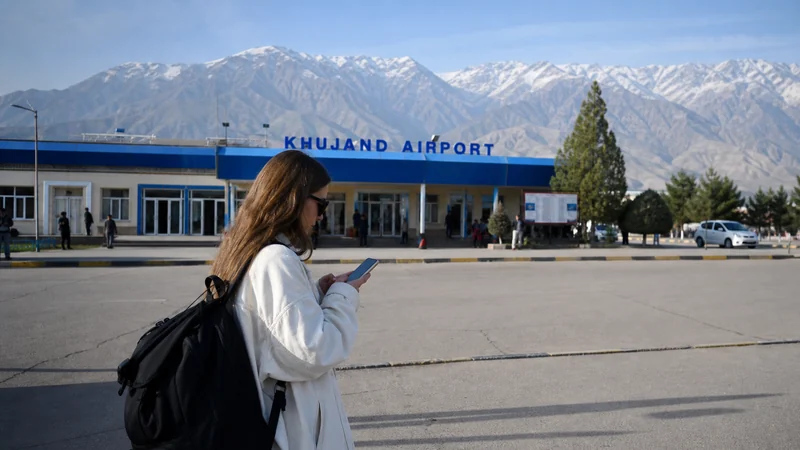 Arriving traveller using a phone outside Khujand Airport