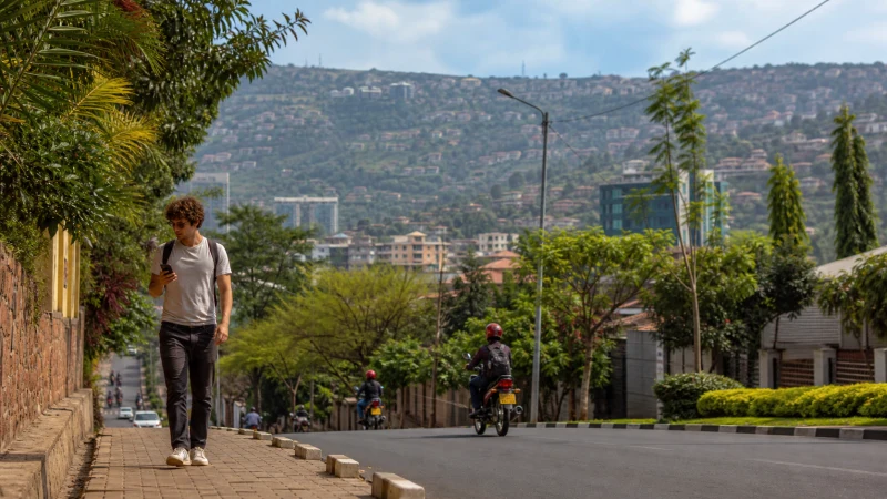 Tourist using a smartphone on a leafy street in Kigali