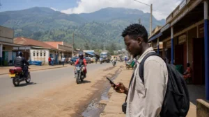 Mbale street scene with a traveller using a smartphone.