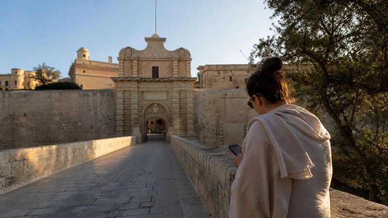 Traveller using a smartphone near Mdina’s historic walls