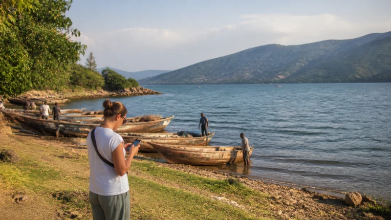 Traveller using a smartphone on the Lake Kivu waterfront in Rubavu