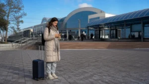 Intercity traveller using a smartphone outside a Karaganda railway station.