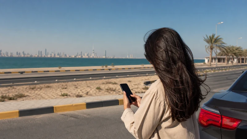 Traveller using a smartphone in a Kuwait setting related to staying online from kuwait city to fahaheel