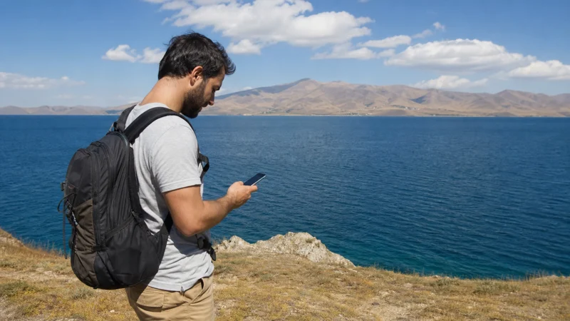 Traveller using a smartphone while using mobile internet around Lake Sevan