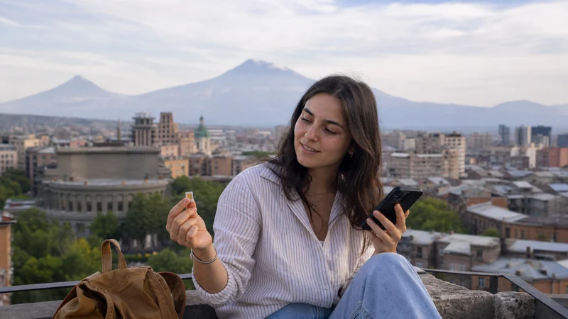 Traveller comparing a physical SIM and eSIM on a Yerevan terrace
