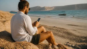 Traveller using a smartphone during traveller on Masirah Island coast