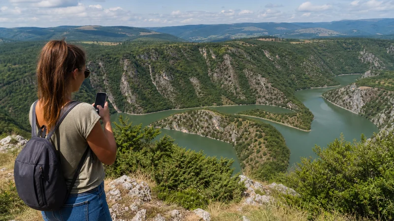 Road traveller using a smartphone above the Uvac river meanders.