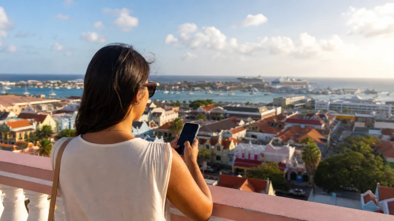 Traveller using mobile service near an Aruba divi divi tree