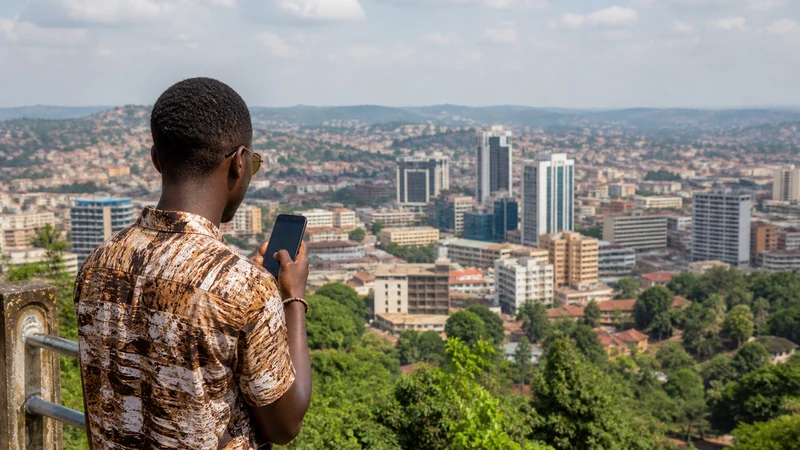 Uganda town skyline with a traveller using a phone.