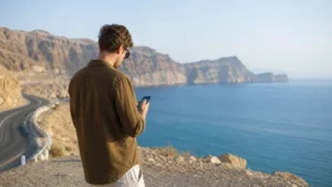 Traveller using a smartphone during traveller on Muscat–Sur route