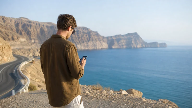 Traveller using a smartphone during traveller on Muscat–Sur route