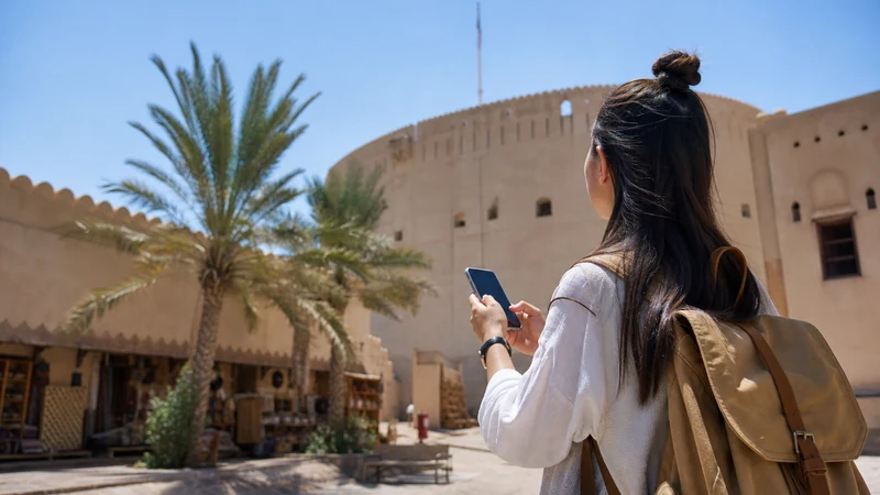 Traveller using a smartphone during traveller near Nizwa Fort