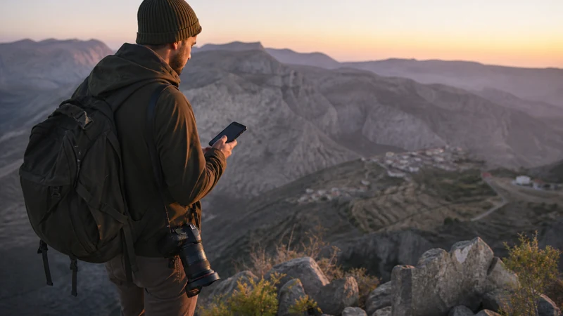 Traveller using a smartphone during travel photographer in Omani mountain landscape